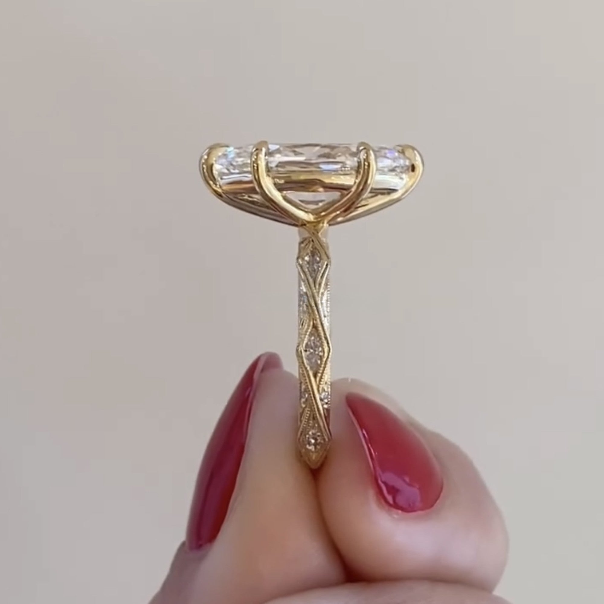 Gold facial roller with gemstones held by a hand against a neutral background