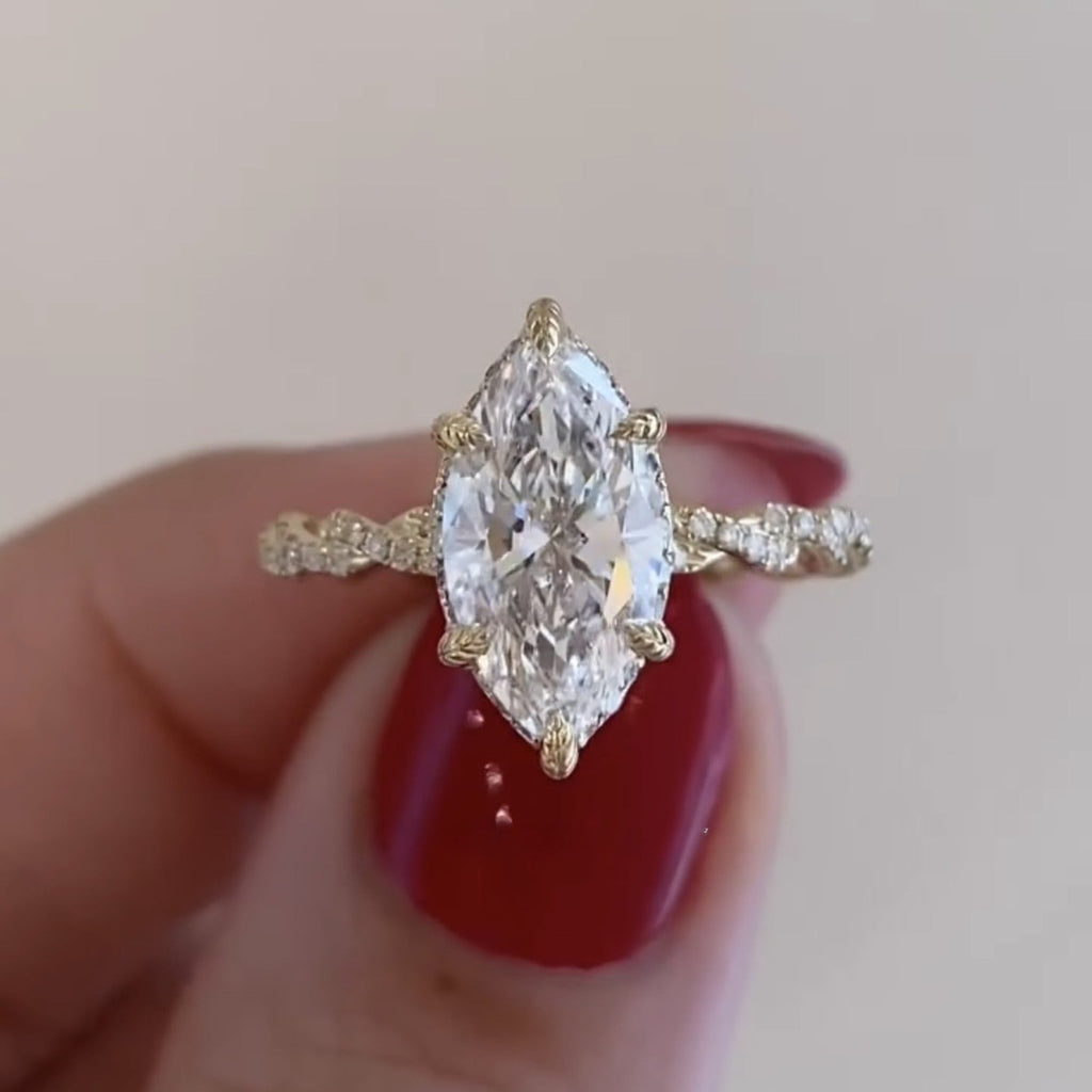 Gold ring with a large diamond held by a hand with red nail polish on a light 
