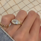 Gold ring with a large diamond on a hand against a checkered