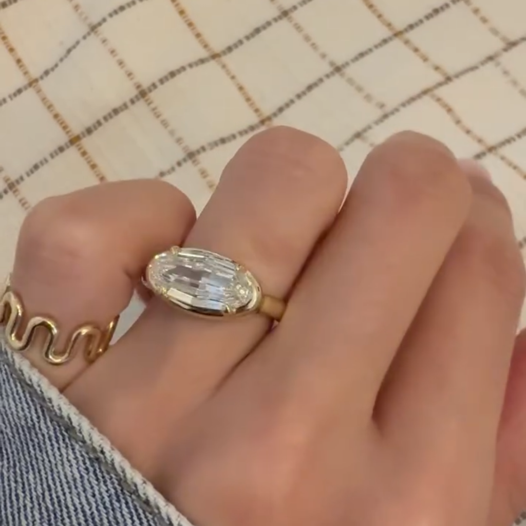 Gold ring with a large diamond on a hand against a checkered