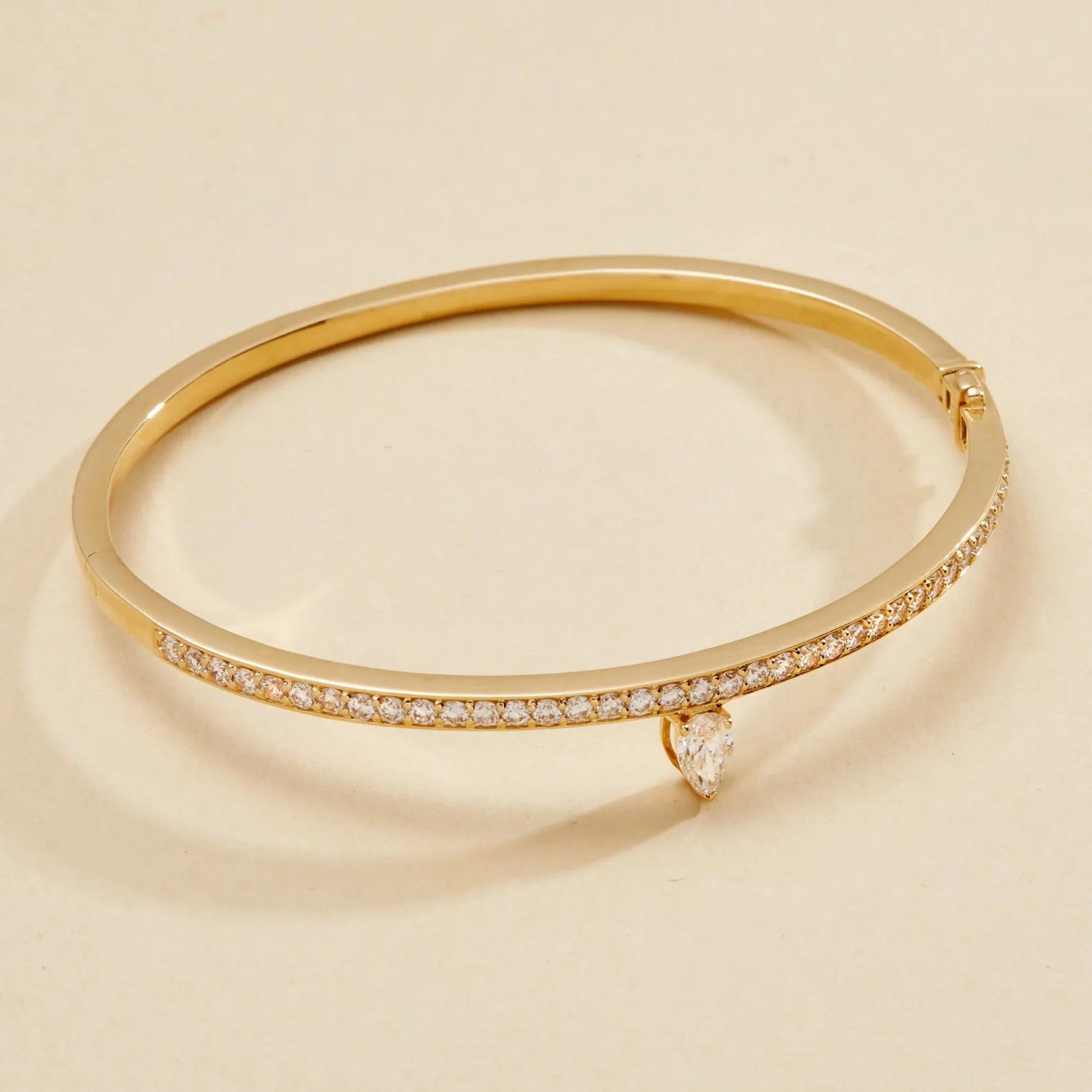 Gold bracelet with diamond accents on a beige 