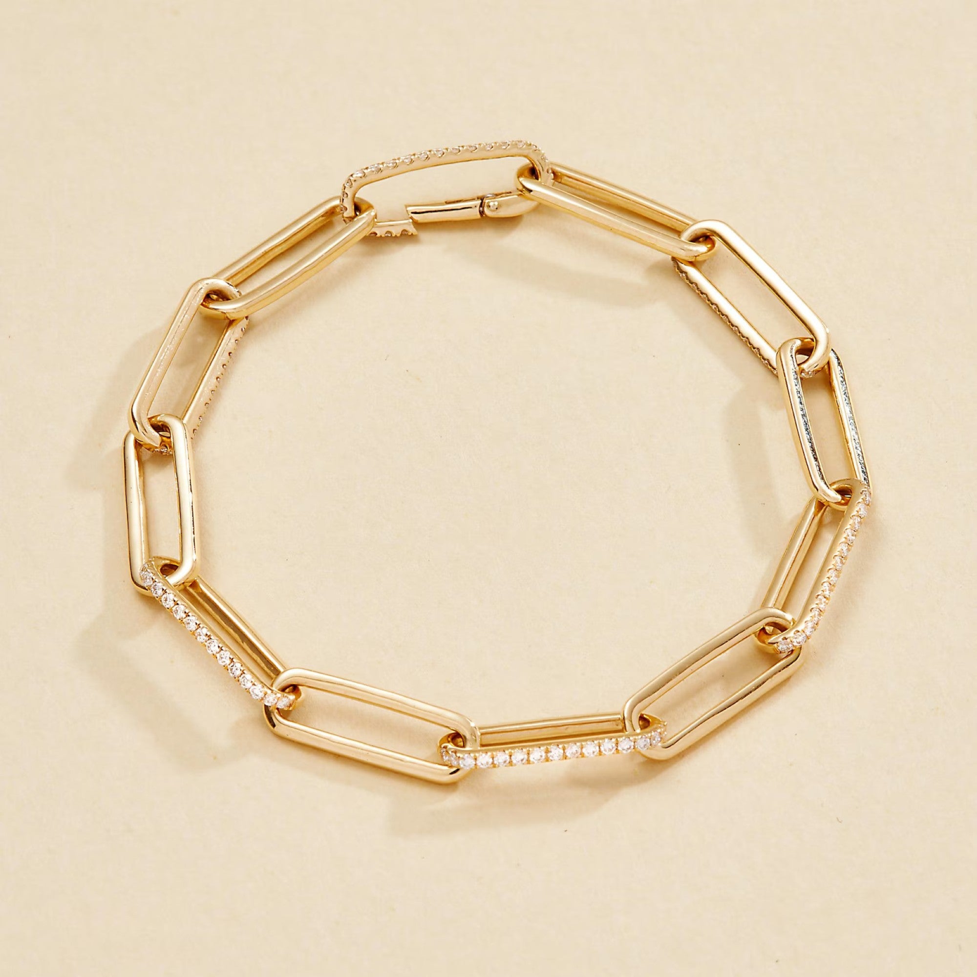 Gold chain bracelet with embedded stones on a beige 