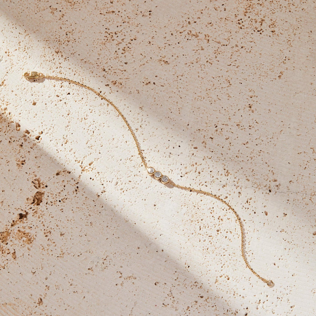 Gold bracelet on a textured beige surface