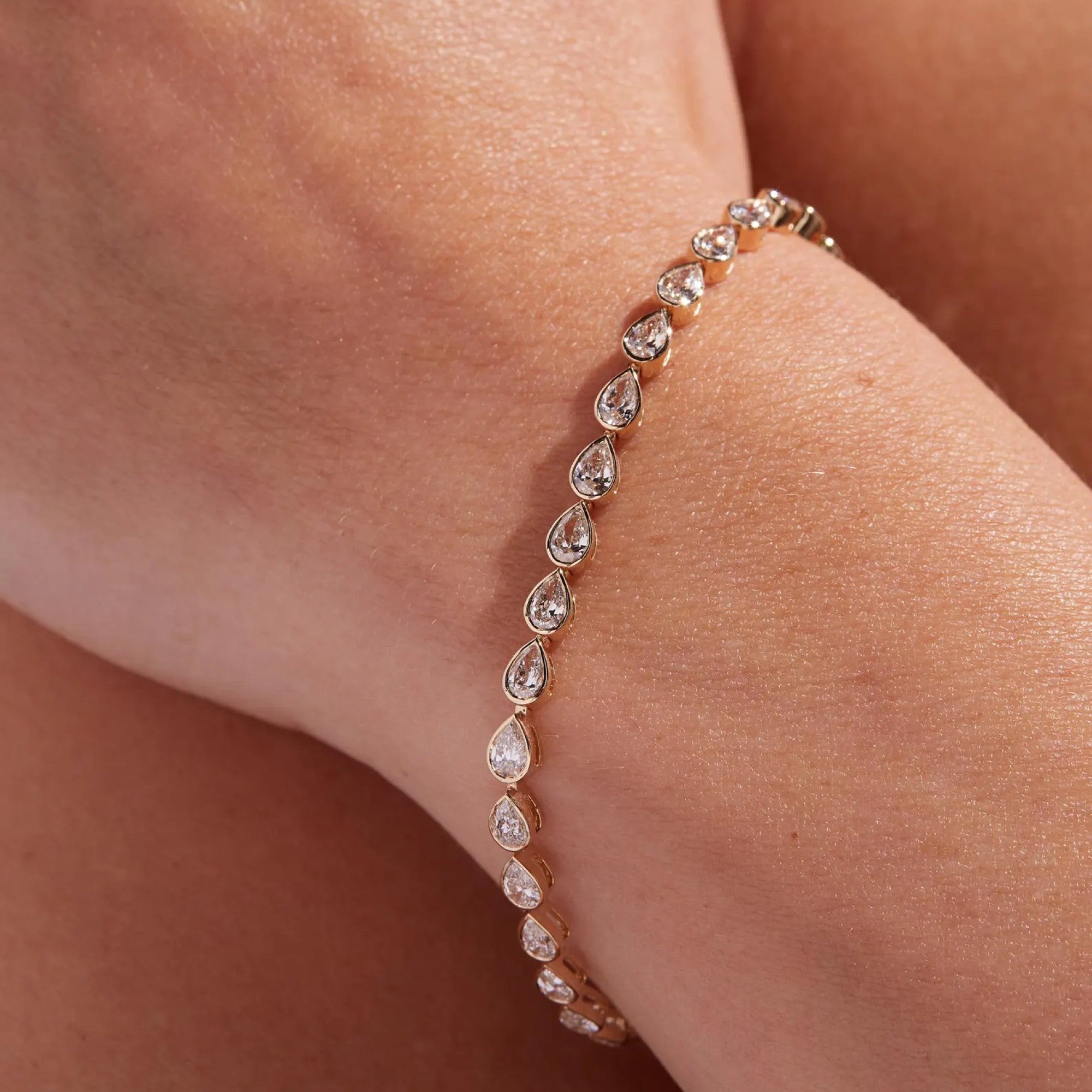 Rose gold bracelet with teardrop-shaped diamonds on a wrist