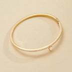 Gold bracelet with small diamonds on a beige 