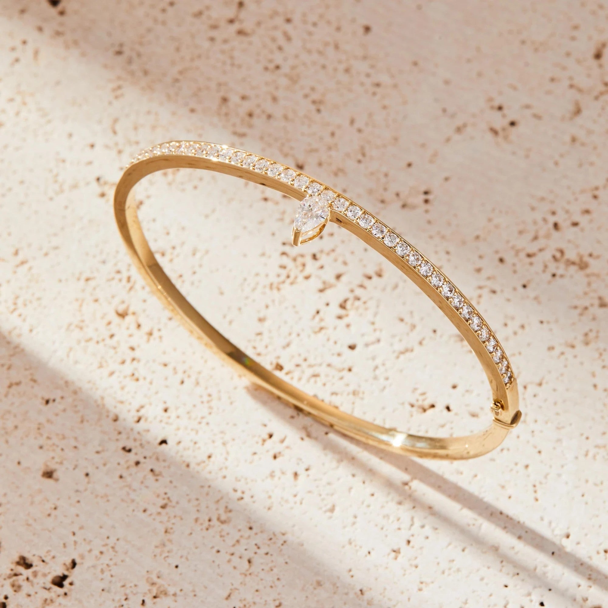 Gold bracelet with diamonds on a beige textured 