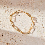 Gold chain bracelet on a textured beige surface