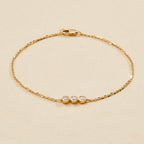 Gold bracelet with three small round diamonds on a beige 