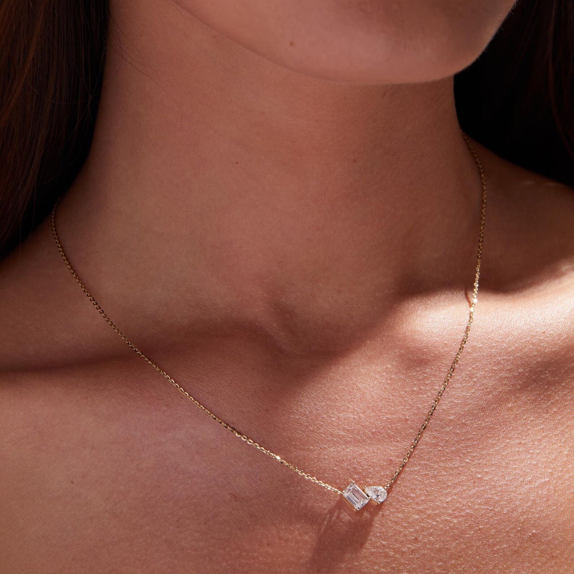 Gold necklace with a diamond pendant on a person's neck