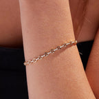 Rose gold bracelet on a wrist against a neutral 