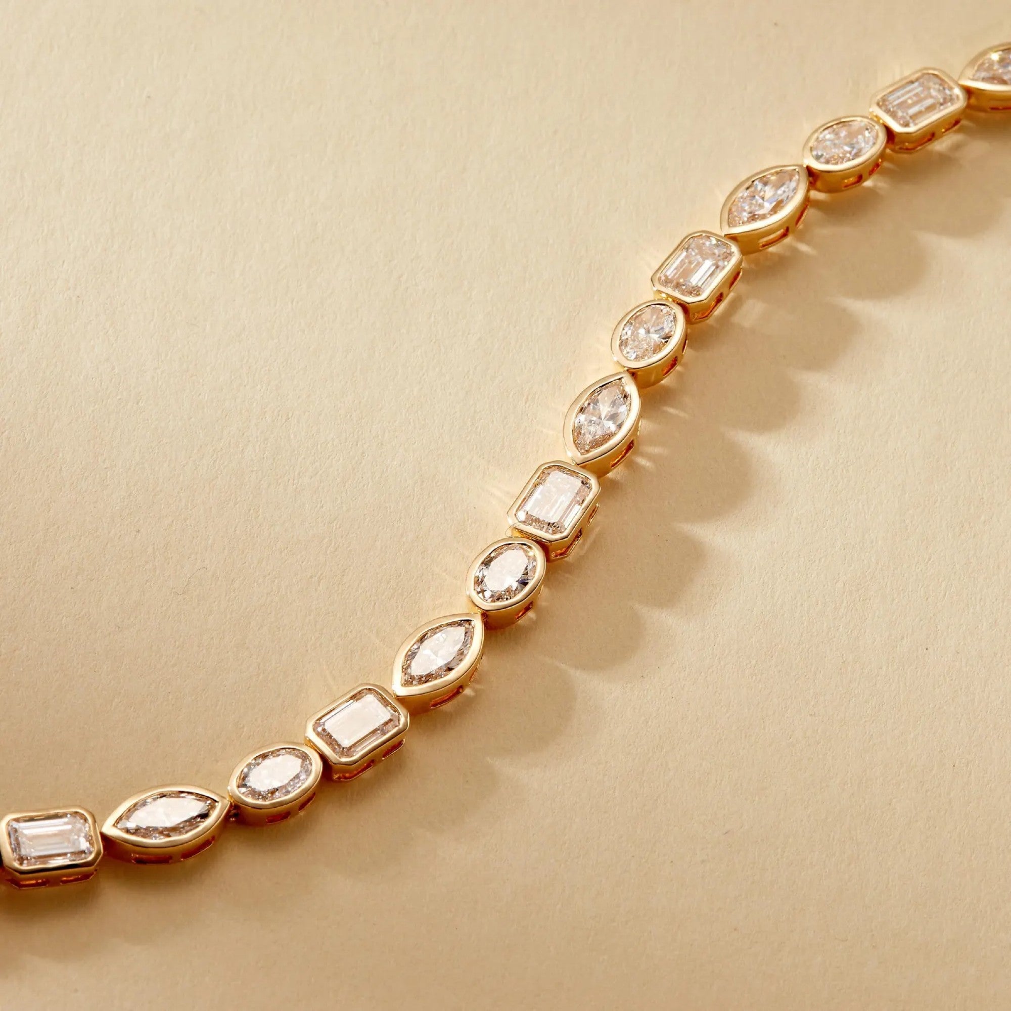 Gold bracelet with diamond-like stones on a beige 