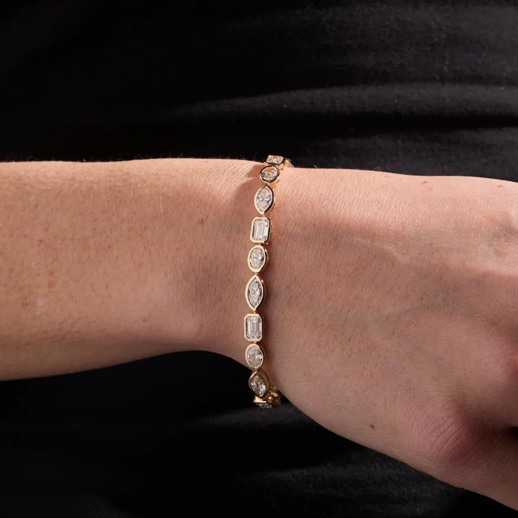 Diamond bracelet on a person's wrist against a black 