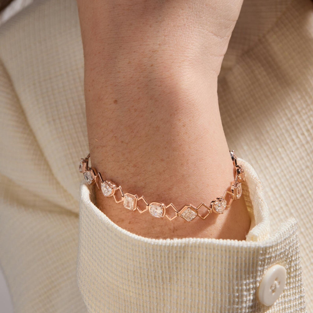Rose gold bracelet with gemstones on a wrist, wearing a beige sweater.