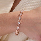 Rose gold bracelet with clear stones on a wrist against a neutral background