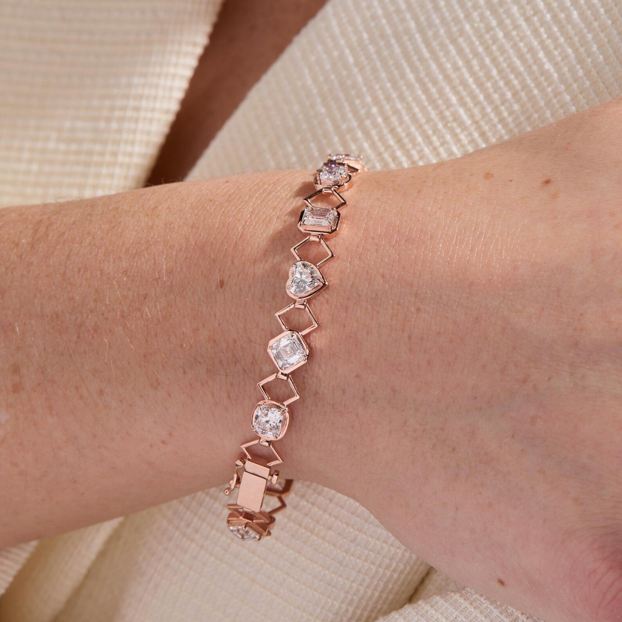 Rose gold bracelet with clear stones on a wrist against a neutral background