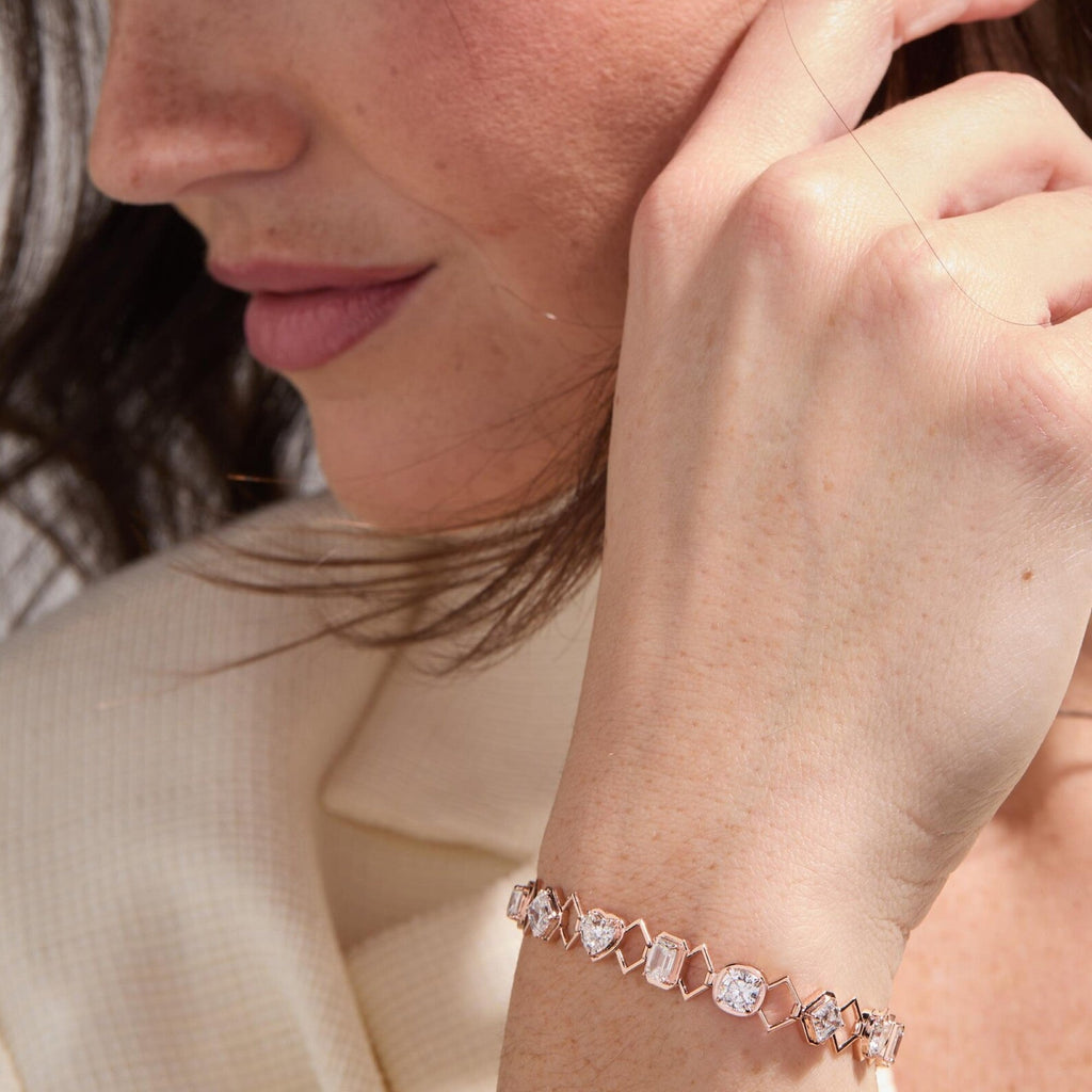 Close-up of a woman wearing a rose gold bracelet with heart-shaped stones.