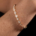 Gold bracelet with diamond accents on a wrist against a neutral background