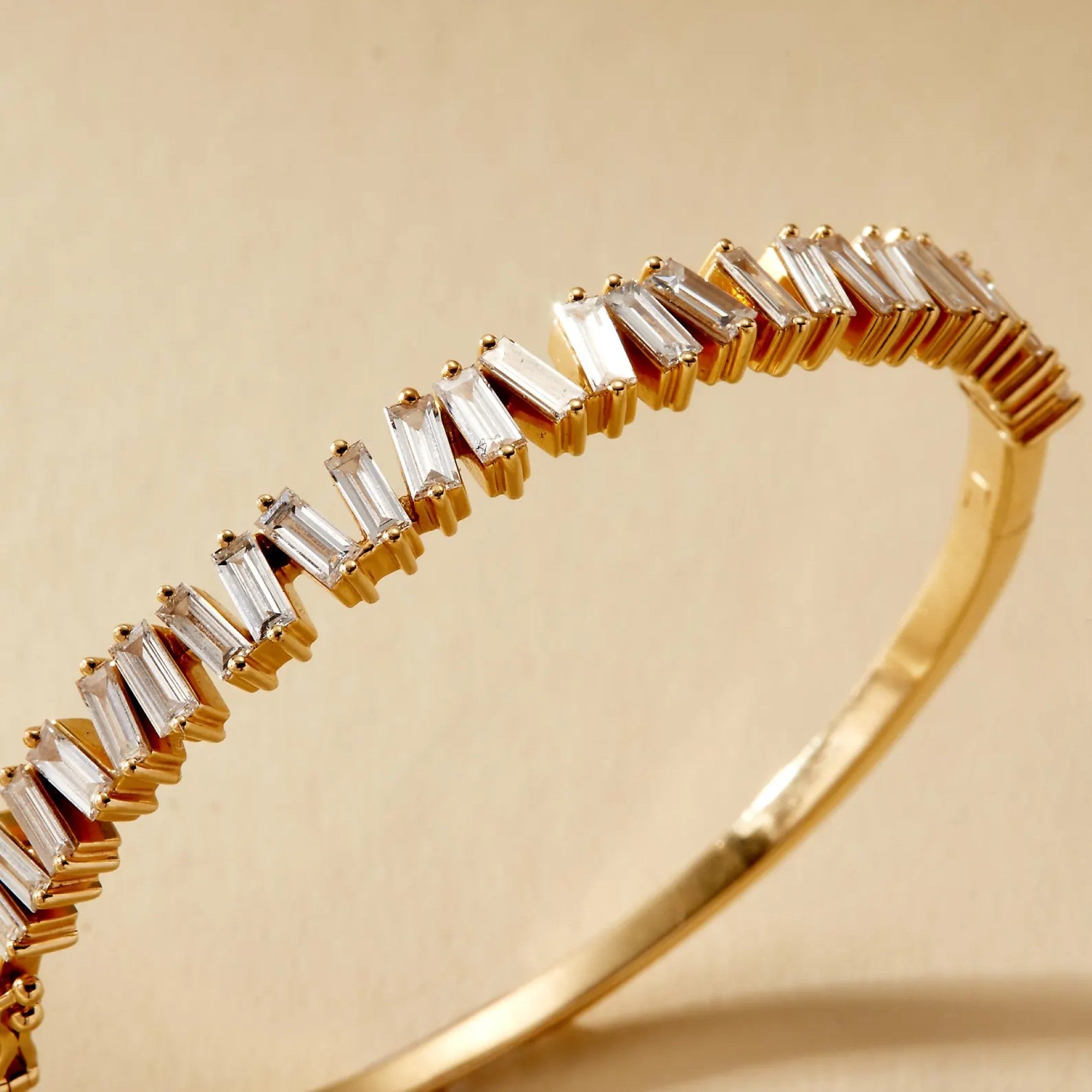 Gold bracelet with baguette-shaped diamonds on a beige 