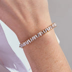 Rose gold bracelet with clear stones on a wrist against a neutral background