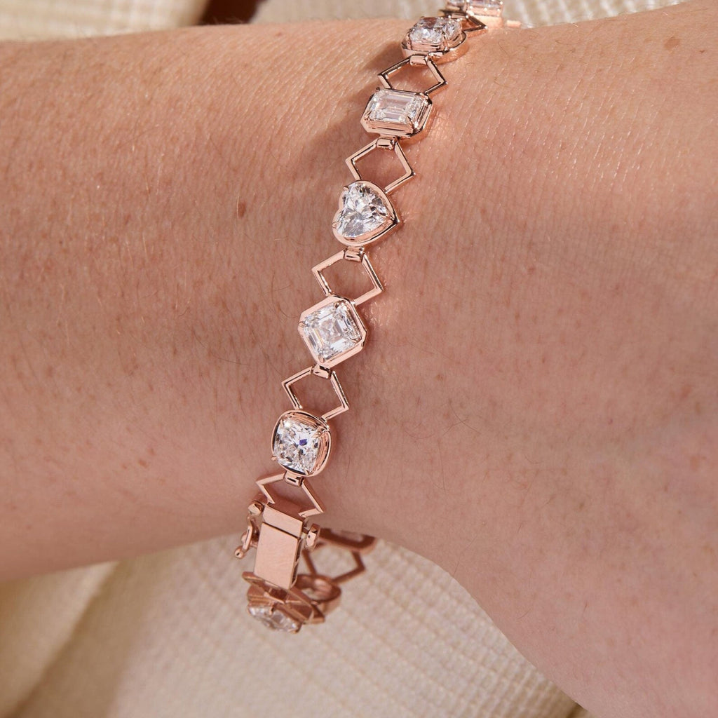 Rose gold bracelet with heart-shaped crystals on a wrist against a neutral 