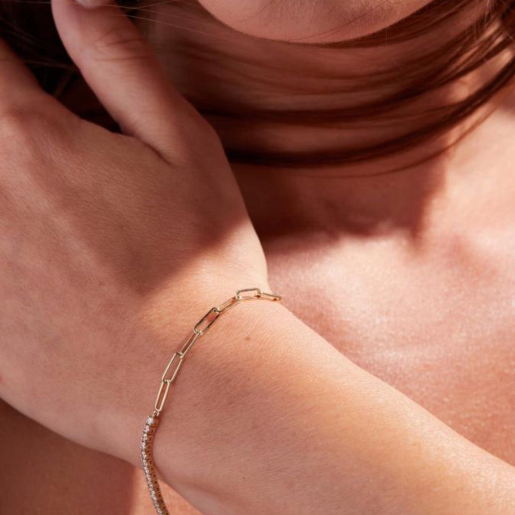 Close-up of a person wearing a gold bracelet on a soft 