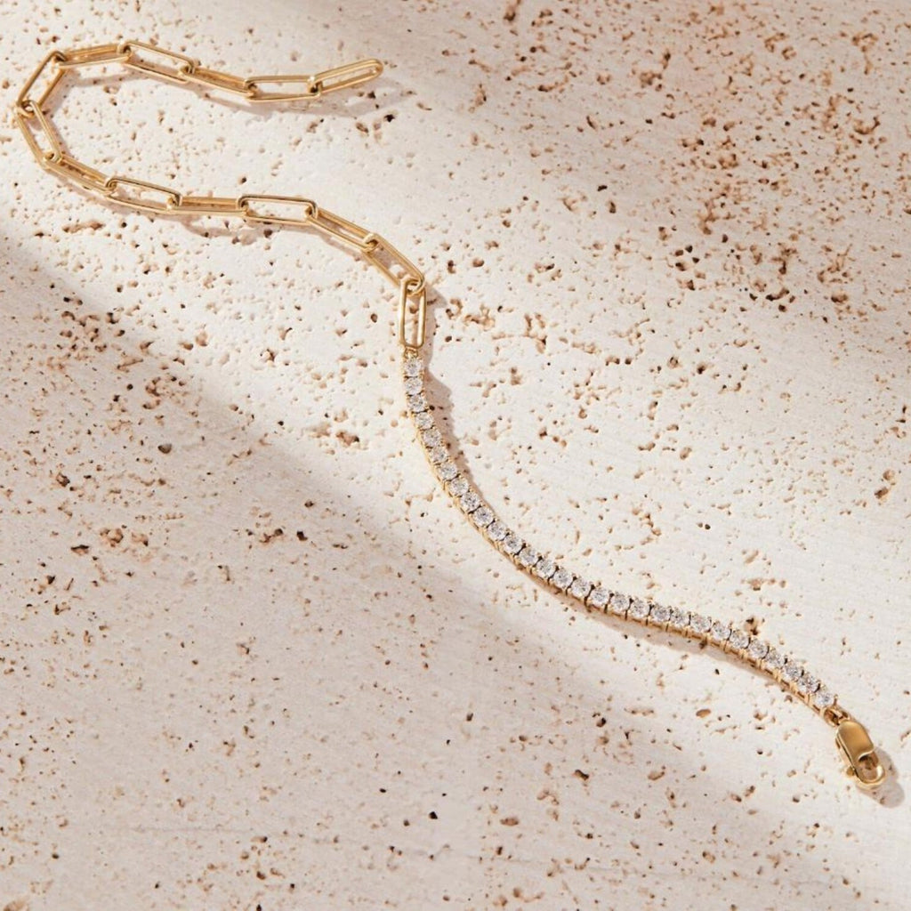 Gold bracelet with clear stones on a textured beige surface