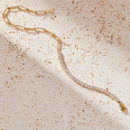 Gold bracelet with clear stones on a textured beige surface