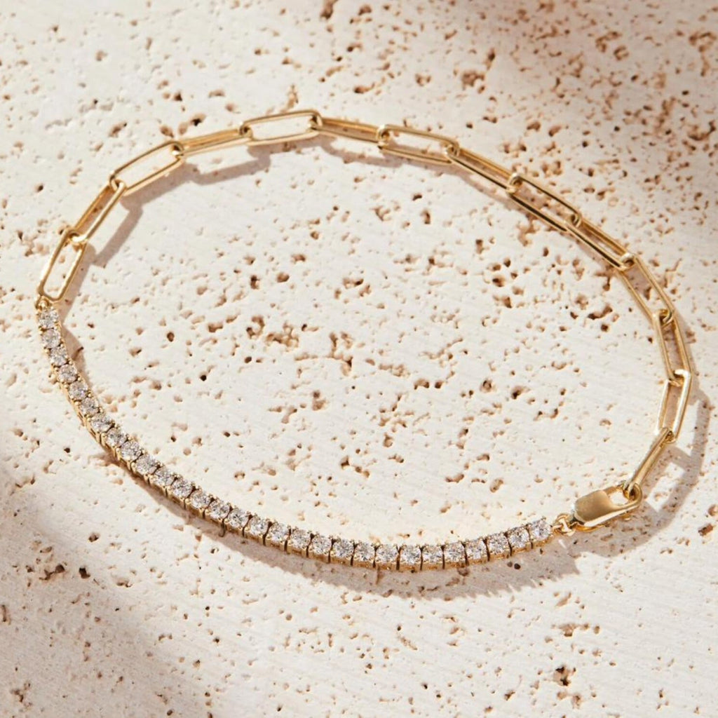 Gold bracelet with clear stones on a textured beige surface