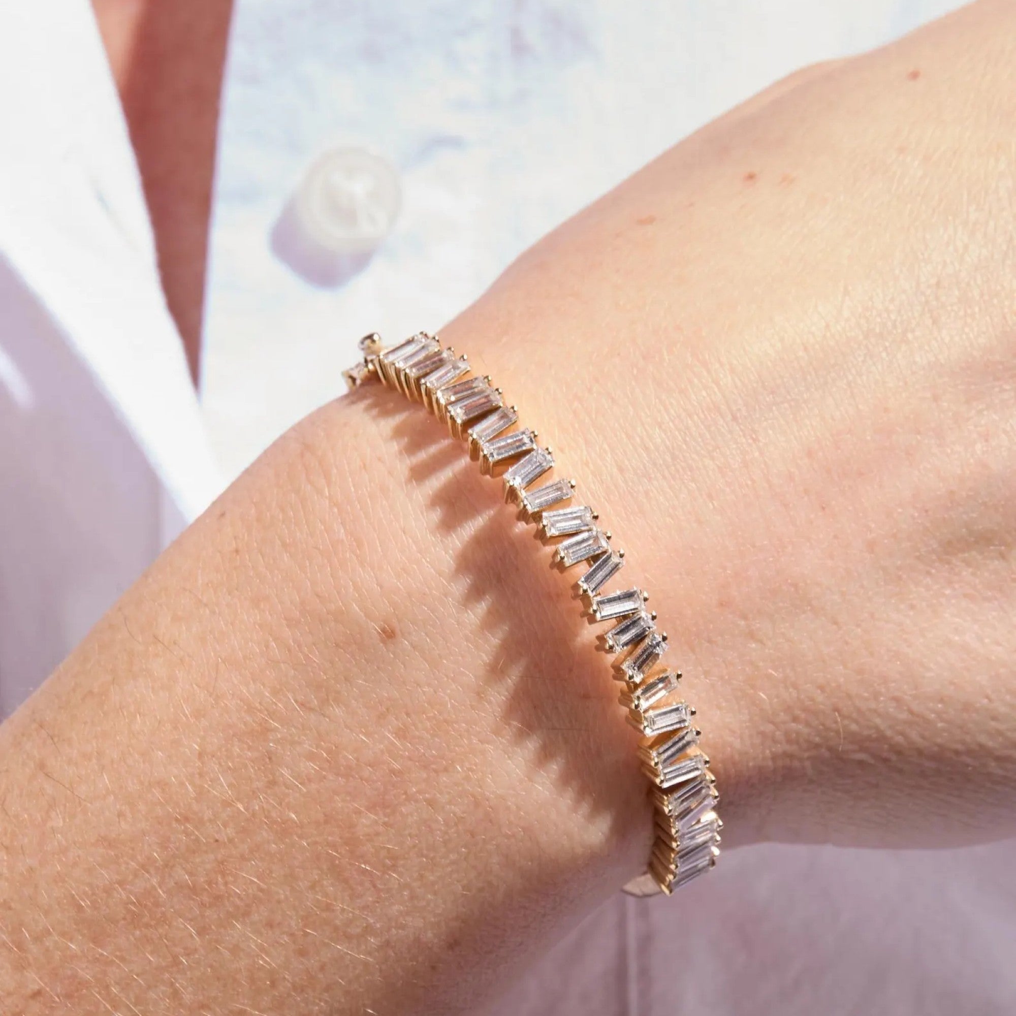 Jewelry bracelet with clear stones on a wrist against a light 