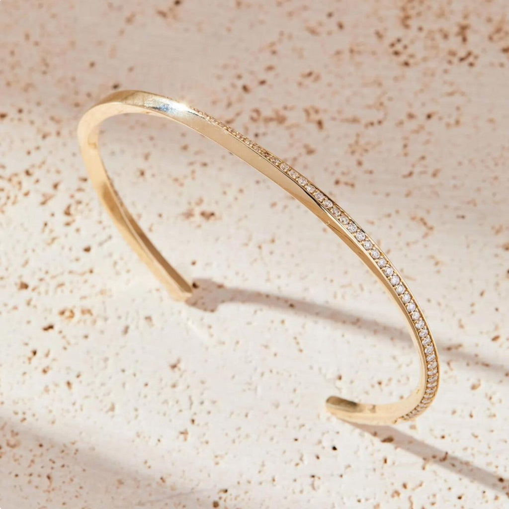 Gold bracelet with small diamonds on a beige textured 