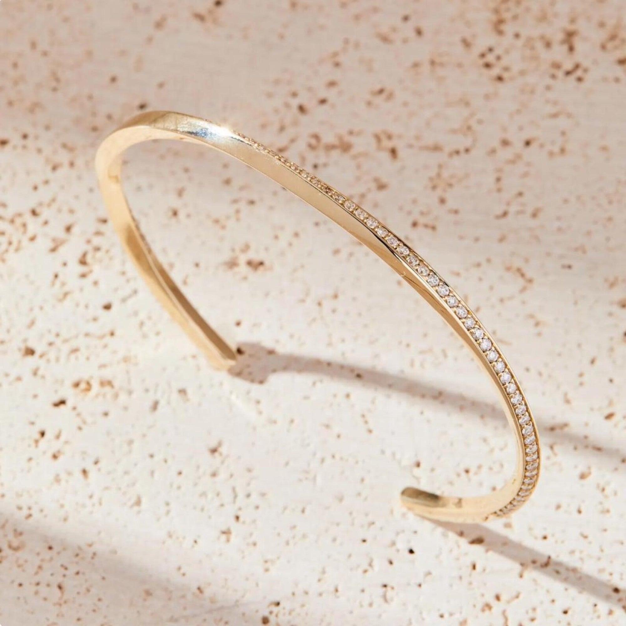 Gold bracelet with small diamonds on a beige textured 
