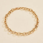 Gold chain bracelet on a beige 
