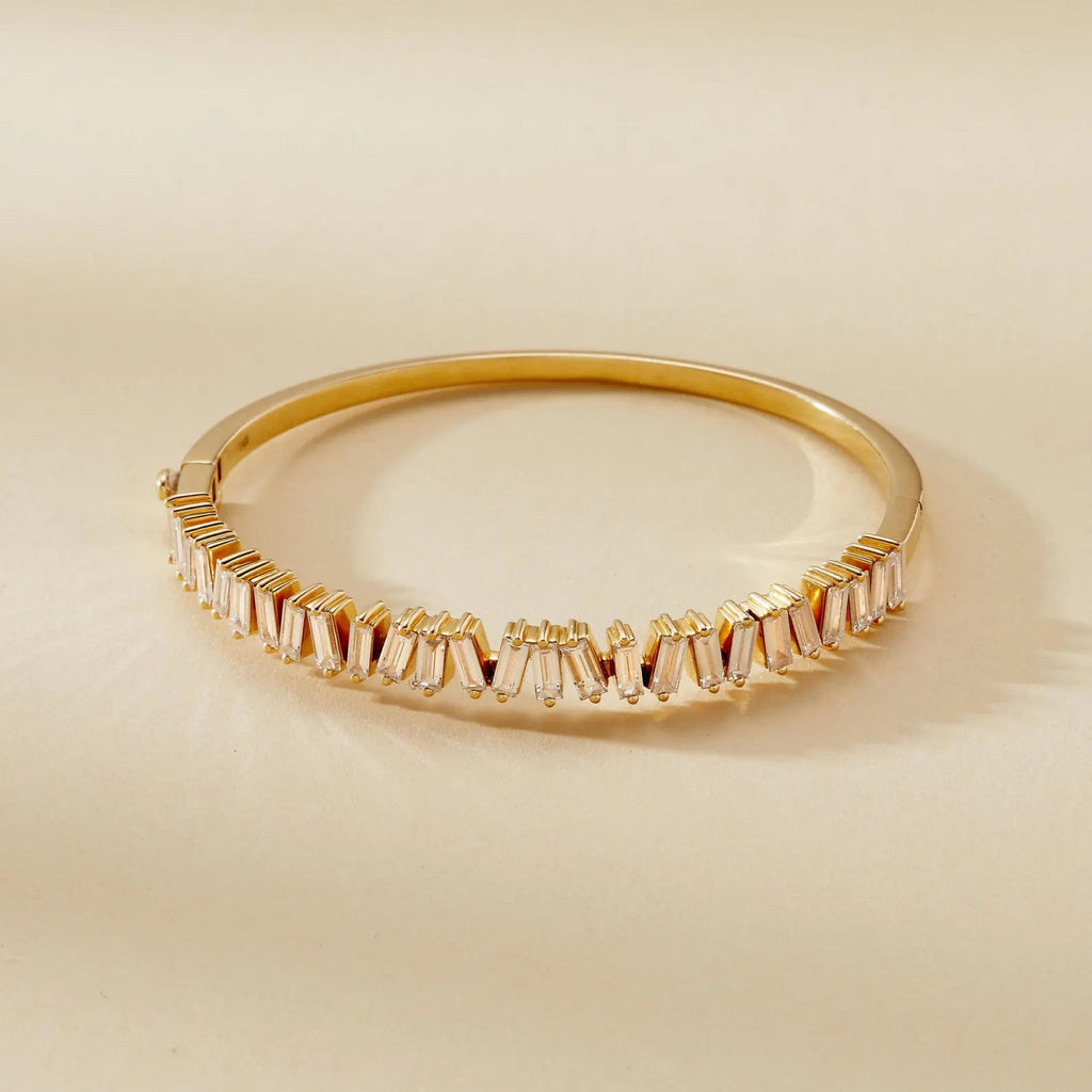 Gold bracelet with baguette cut stones on a beige 