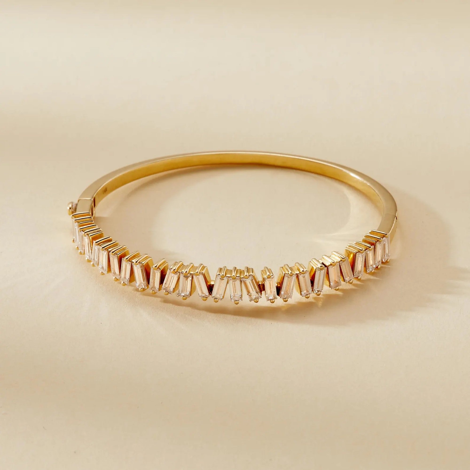 Gold bracelet with baguette cut stones on a beige 