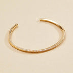 Gold bracelet with small stones on a beige 