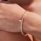 Rose gold bracelet with diamond accents on a wrist against a neutral 