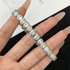 Silver bracelet with emerald-cut gemstones on a hand against a white 