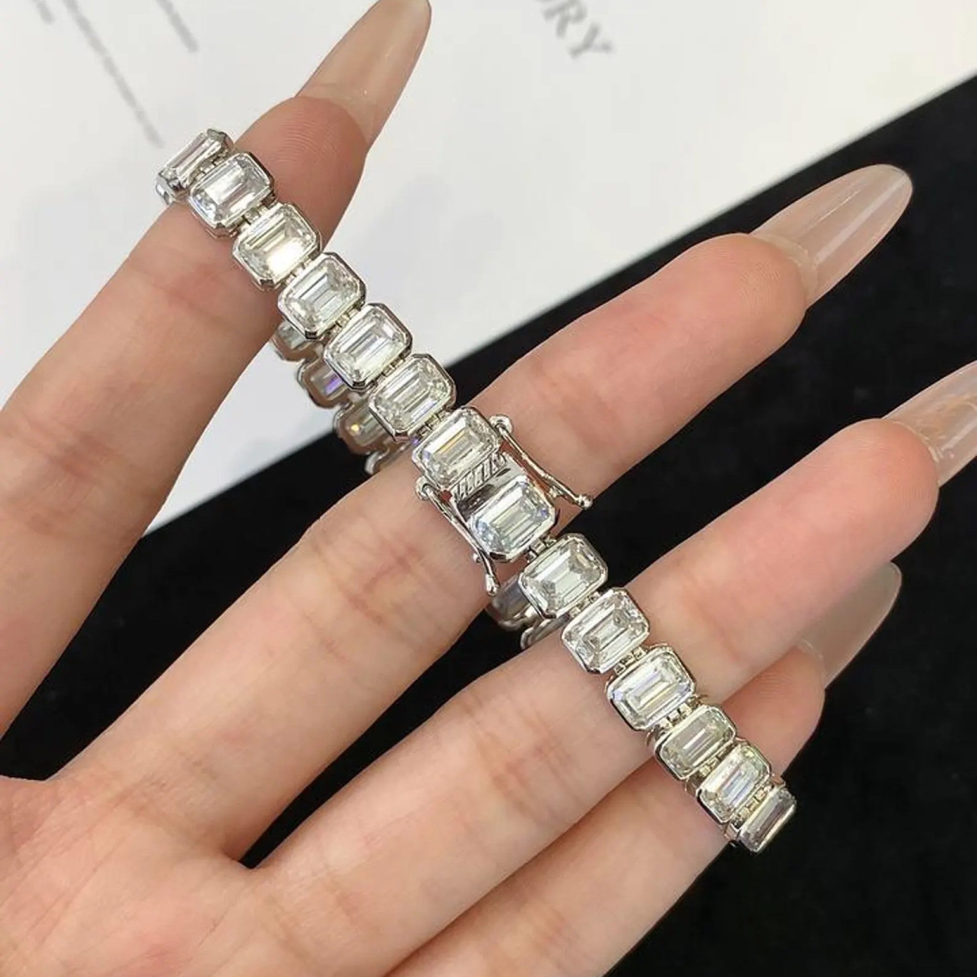 Silver bracelet with emerald-cut gemstones on a hand against a white 